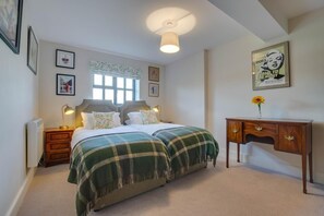 Ein Schlafzimmer mit einem Bett, Nachttischen, einem Schreibtisch und einem Fenster.