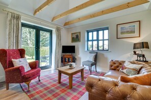 A living room with a red armchair, a brown sofa, a wooden coffee table, and a television on a stand. - 2 Bed in Wrotham (oc-ts732) (Stansted)
