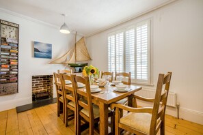 Ein Essbereich mit Holztisch und Stühlen, einer Vase mit Sonnenblumen und einem Segel an der Wand.
