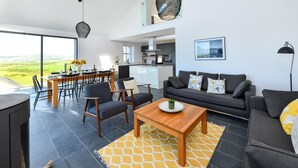 A spacious living area with a dining table, sofa, and kitchen in the background.