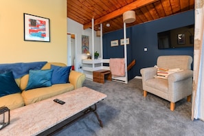 A living room with a sofa, armchair, and coffee table. There is a bookshelf and a lamp. - 1 Bed in Pwllheli (oc-7marin) (Pwllheli)
