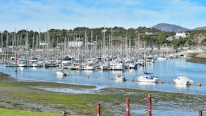 A marina with numerous boats docked, surrounded by greenery and hills. - 1 Bed in Pwllheli (oc-7marin) (Pwllheli)