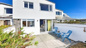 A modern two-story house with a patio area featuring blue chairs and a small table. - 1 Bed in Pwllheli (oc-7marin) (Pwllheli)