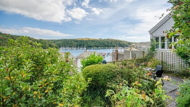 A coastal view with a marina, a white building with a balcony, and lush greenery. - 2 Bed in Fowey (oc-secret) (Fowey)