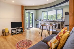Una sala de estar moderna con un televisor de pantalla plana, un sofá y un comedor con mesa y sillas.