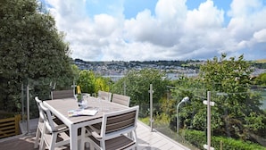 Eine Terrasse mit Essplatz, mit Blick auf eine Stadtlandschaft und einen Fluss.