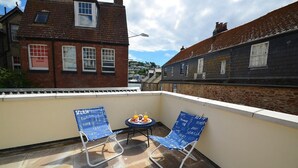 Eine kleine Terrasse im Freien mit zwei blauen Stühlen und einem Tisch, gedeckt mit Speisen und Getränken.