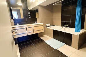 Een moderne badkamer met een badkuip, wastafel en spiegel.