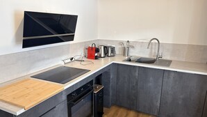 A modern kitchen with a built-in oven, a sink, and a flat-screen TV mounted above the counter. - Le refuge d'Anny - Three Bedroom Apartment, Sleeps 8 (Vaujany)