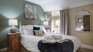 Un lit bien fait, recouvert d’une couverture moelleuse, une table de chevet avec une lampe et un tableau accroché au mur.