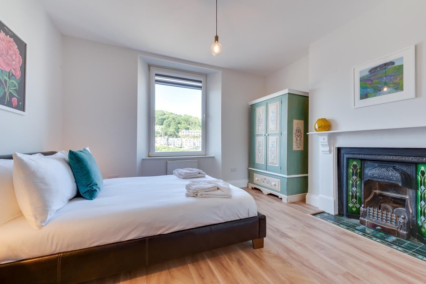 Ein Schlafzimmer mit Bett, Fenster, einem grünen Schrank und einem Kamin.