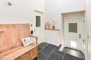 A hallway with a wooden bench, a cabinet, and a door.