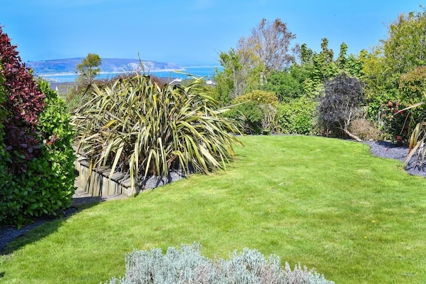 A well-maintained garden with a variety of plants and a clear view of the ocean in the background.