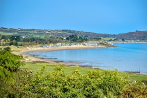 A coastal area with a beach, houses, and greenery.