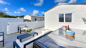 Une terrasse dotée de mobilier d’extérieur, d’une table à manger et d’une petite table pour les boissons.