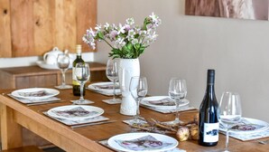 A wooden dining table set with plates, glasses, and a bottle of wine. - 3 Bed in Llanbedrog (oc-brntr) (Llanbedrog)