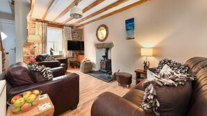 A cozy living room with a fireplace, leather sofas, and a stone wall. - 3 Bed in Llanbedrog (oc-brntr) (Llanbedrog)