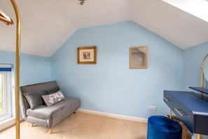 A room with a grey sofa, a blue wall, a framed picture, a mirror, and a blue ottoman. - 1 Bed in Elton (oc-dctco) (Elton)