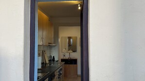 Un pasillo estrecho que conduce a una cocina con armarios de madera y piso de baldosas negras.