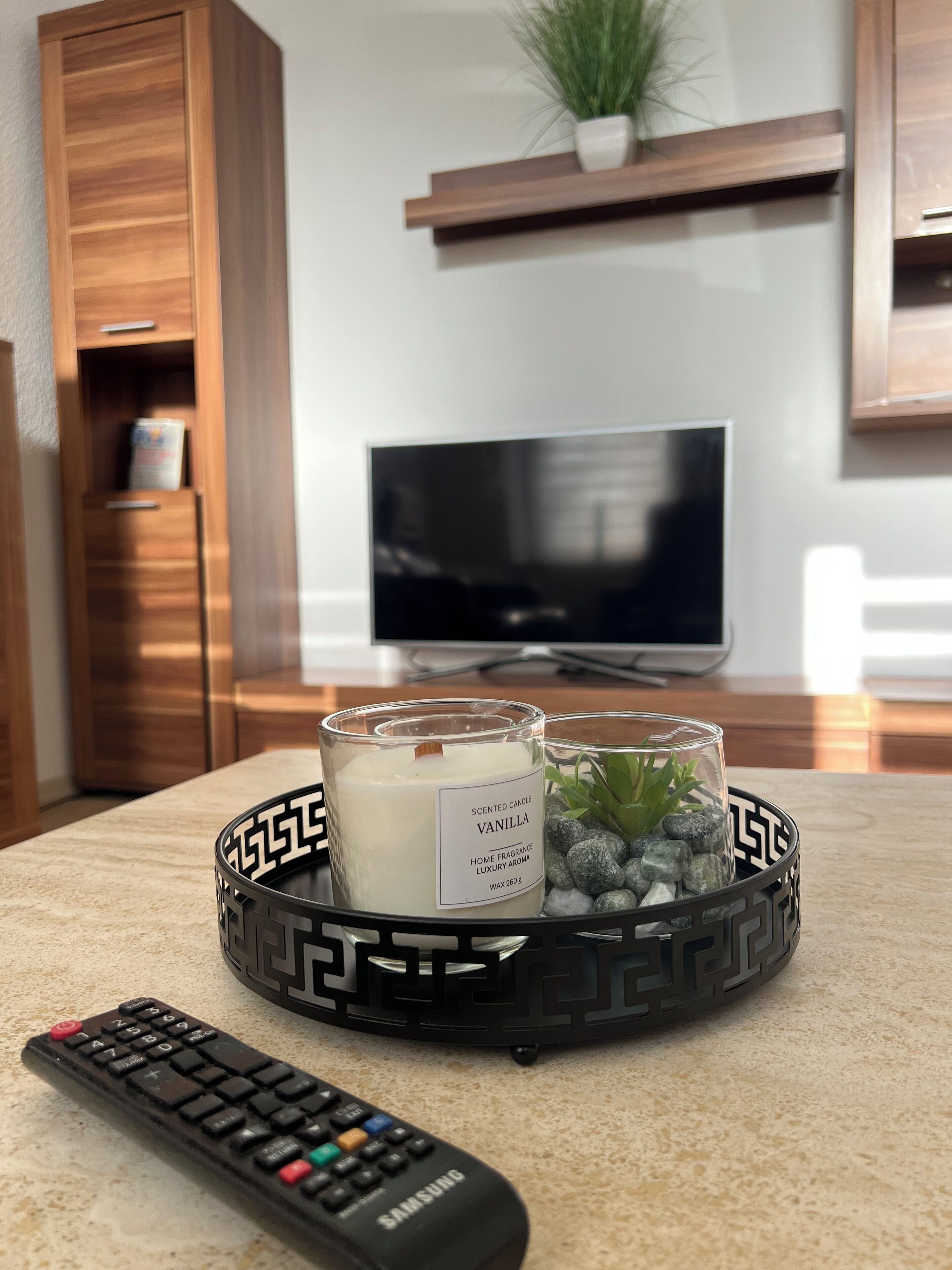 A remote control, a scented candle, and a decorative tray on a countertop.