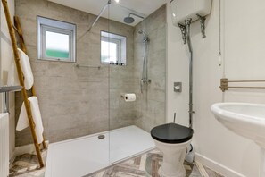 Ein Badezimmer mit Dusche, Toilette und Fenster.