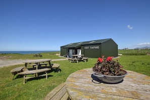 A coastal picnic area with wooden benches and a small building labeled "GWT ATWIS". - 4 Bed in Rhoshirwaun (oc-bow324) (Rhoshirwaun)