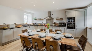 Una cocina moderna con una isla central, muebles blancos y electrodomésticos de acero inoxidable.
