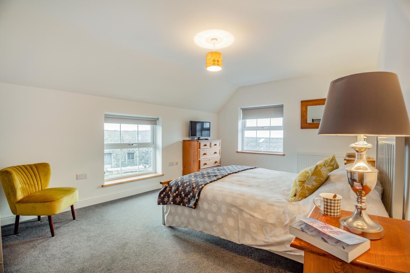 A bedroom with a bed, a chair, a TV, and a lamp.