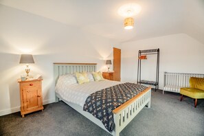 A bedroom with a bed, bedside tables, a radiator, a chair, and a hanging light fixture. - 4 Bed in Rhoshirwaun (oc-bow324) (Rhoshirwaun)