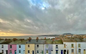 A row of terraced houses with a view of the sea and hills in the background. - 3 Bed in Scarborough (oc-s113) (Scarborough)