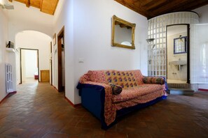 A hallway with a patterned sofa, a mirror, and a tiled wall. - Sweet House in Macci Street (Firenze)