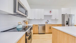A modern kitchen with white cabinets, stainless steel appliances, and a wooden countertop. - Modern Retreat • Private Pergola • Pool • Fire Pit (Houston)