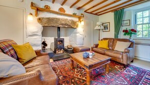 Una sala de estar acogedora con chimenea de piedra, sofás de cuero, alfombra estampada y una mesa de centro de madera.