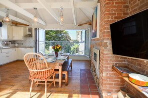 A kitchen with a dining table, chairs, and a view through the window. - 5 Bed in St. Ives (oc-baktre) (St Ives)