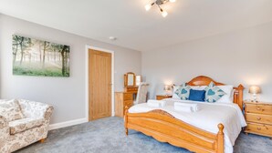 A bedroom with a wooden bed, a chair, a dresser, and a painting on the wall. - 2 Bed in Fowey (oc-jackda) (Fowey)
