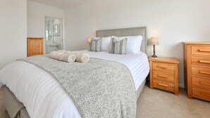 Une chambre à coucher comprenant un lit, une table de chevet, une commode et un luminaire suspendu.