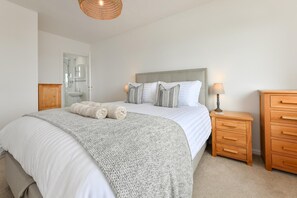 Ein Schlafzimmer mit Bett, Nachttisch, Kommode und Pendelleuchte.