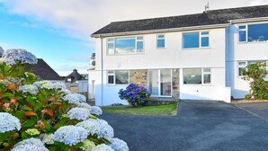 A two-story residential building with a driveway and a garden with hydrangeas. - 4 Bed in Abersoch (oc-21tan) (Abersoch)