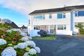 A two-story residential building with a driveway and a garden with hydrangeas. - 4 Bed in Abersoch (oc-21tan) (Abersoch)