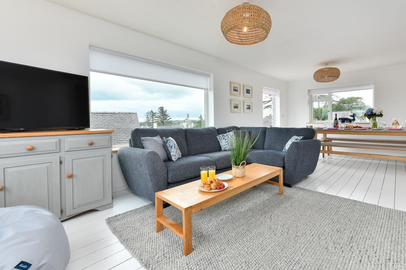A modern living room with a grey sofa, wooden coffee table, and a flat-screen TV on a cabinet.