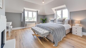 Quarto com uma cama grande, uma mesa de cabeceira, uma luminária e uma janela.