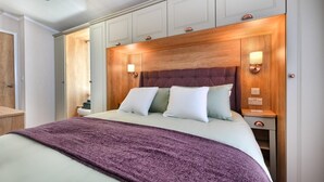 A neatly arranged bedroom with a bed, pillows, a wooden headboard, and bedside lamps. - 2 Bed in Abersoch (oc-atacam) (Abersoch)