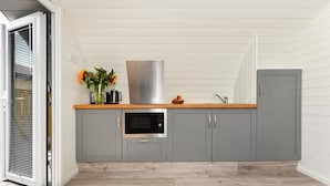 Una cocina compacta con gabinetes grises, una campana extractora de acero inoxidable, un horno integrado y una encimera de madera.
