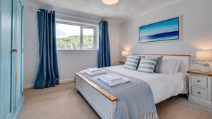 A bedroom with a bed, bedside tables, a window with curtains, a painting, and a ceiling light fixture. - 2 Bed in Looe (oc-msweet) (Looe)