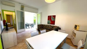 A compact living space with a dining area, kitchenette, and a sofa. - VILLA DOGI NORTH - A2 6+0 - B80F15 (Bibione Pineda)