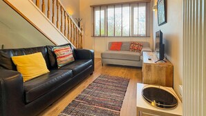 A living room with a black leather sofa, a patterned rug, a wooden coffee table, and a television. - 2 Bed in Talwrn (oc-wai228) (Ysgubor Hen)