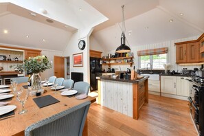 Un'ampia cucina con isola centrale, mobili in legno e zona pranzo con tavolo e sedie per quattro persone.
