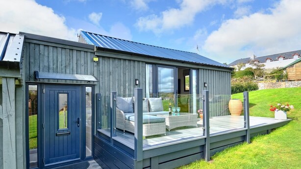 A modern house with a deck, a glass door, and a small outdoor seating area. - 2 Bed in Abererch (oc-glwysf) (Abererch)