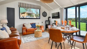 A modern living room with a sofa, coffee table, and dining area with chairs. - 2 Bed in Abererch (oc-glwysf) (Abererch)