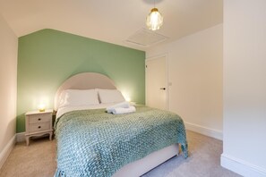 Ein Schlafzimmer mit Bett, Nachttisch und einer Pendelleuchte.